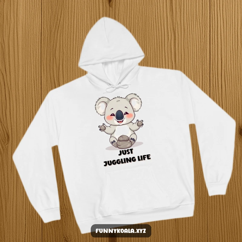 Funny Koala Hoodie: A playful koala with a mischievous grin attempts juggling three rocks, offering cozy humor and a unique gift.